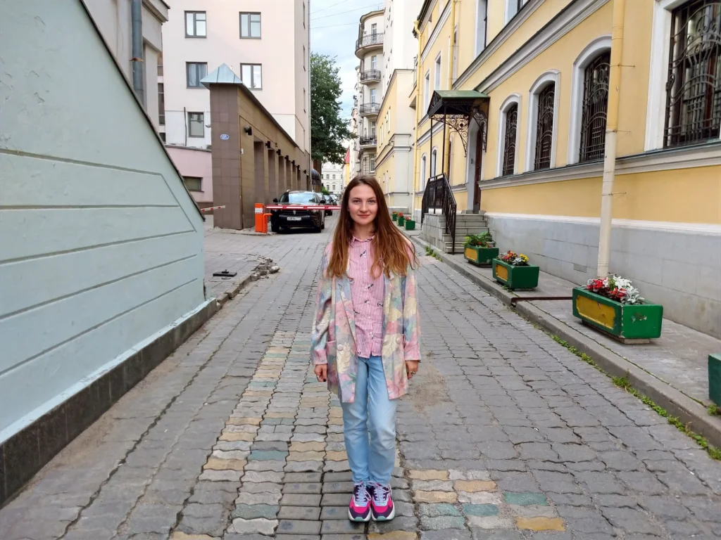Женщина стоит на мощёной улице между зданиями